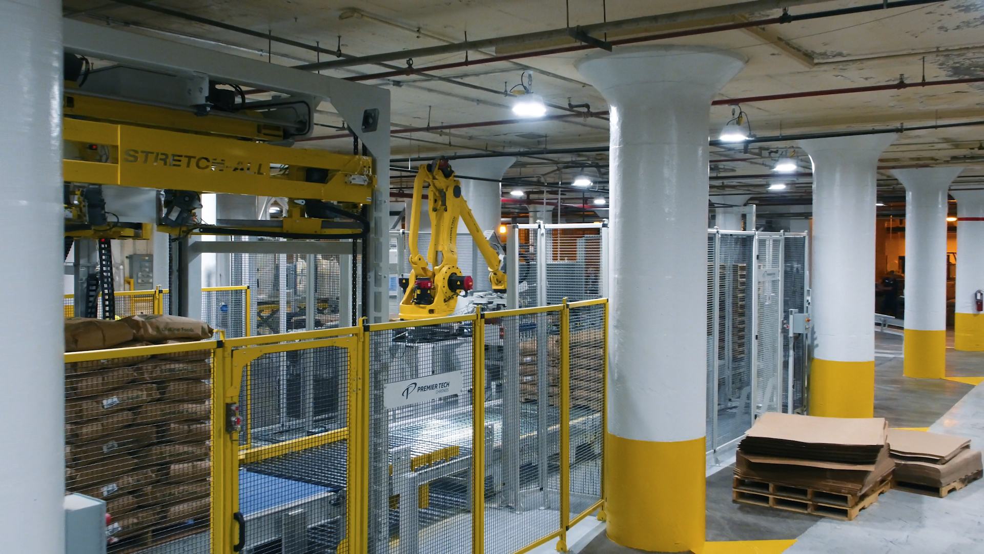 A robotic bag palletizer creates perfectly uniform stacks of bags on a pallet, which then receives a stretch hood.