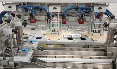 Seen here are three carton forming cavities and, in the foreground, cans that will be top-loaded into the cartons.