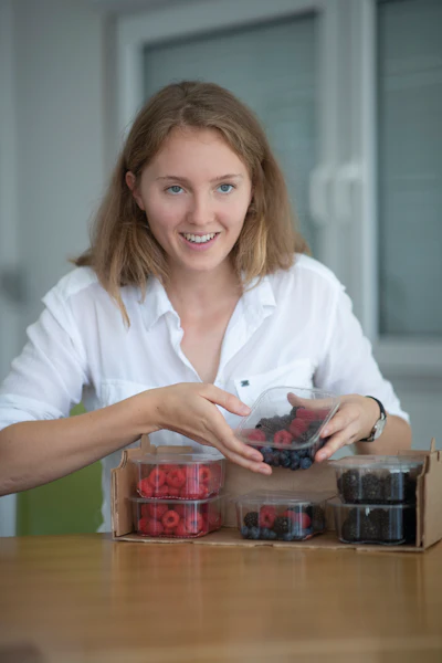 CEO Annika Baumann proudly showing secondary packaging filled with berries in rPET trays with flexible film lidding.
