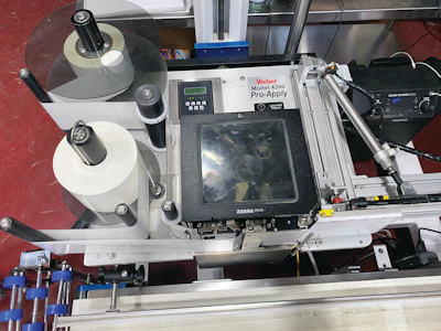 After cases are taped shut, a print-and-apply labeler brings the line to a close.