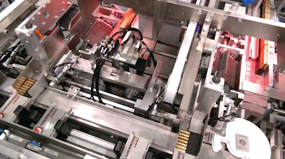 Trays of ammunition from the two-up infeed are oriented to lay on their sides before pushers load them into cartons.