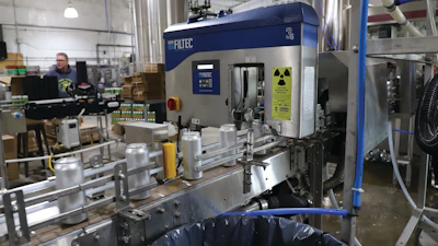 Filled and seamed cans get a fill-level check via Filtec equipment prior to date coding, accumulation, and labeling.