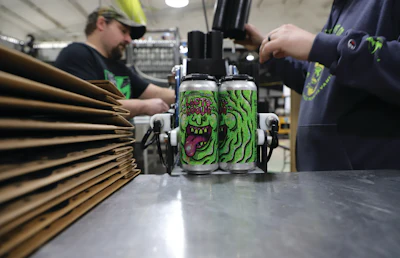 After PakTech can handles are applied to labeled cans, operators pack cans into pop-up trays in a pack-off station that ends the contiguous line.
