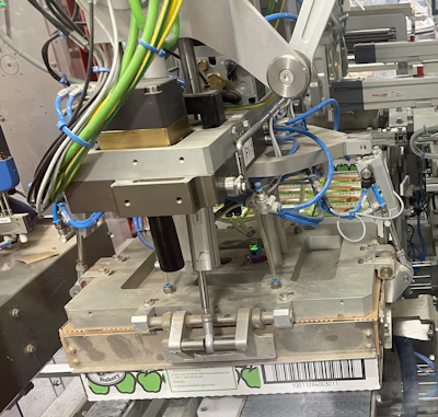 Shown here is the end-of-arm tooling that closes and compresses a corrugated lid onto the 48-count corrugated tray of cartoned pies.