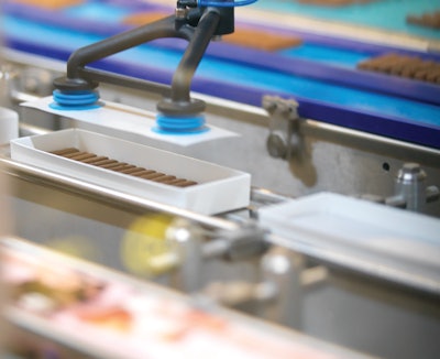 In an added module, wax paper is cut from rollstock, and placed by SCARA robot with vacuum grippers between layers of product.