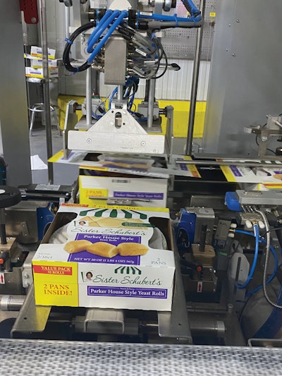 The tooling on this two-axis robotic pusher presses the top flap closed. Then the pusher slides the finished carton at a right angle to a staging area. In doing so, the pusher pushes the preceding twin-pack carton out of the staging area and onto another right angle conveyor takeaway that leads toward the case packing station.