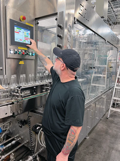 An operator interacts with the HMI on the GAI monoblock bottle filler and crowner.