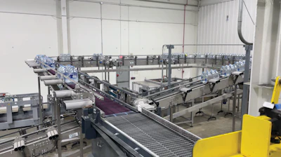 Shrink-wrapped multipacks flow to a palletizer via AMT conveyor.