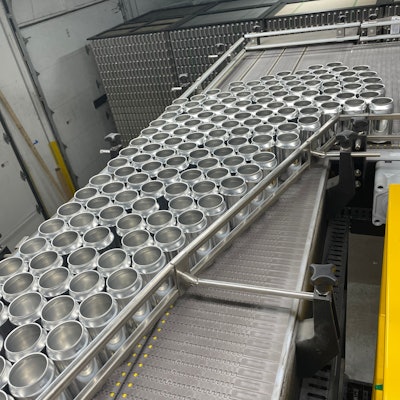 Depalletizing of bright stock cans is done on a GR-X overhead depalletizer in the warehouse. Cans are single-filed and conveyed through a wall into the packaging hall.