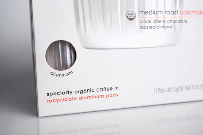 A die-cut window in the coffee carton provides a view of one of the aluminum pods inside the carton.