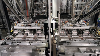 Two delta-style robots pick and place groups of cartons onto sleeves that then proceed to folding and adhesive application.