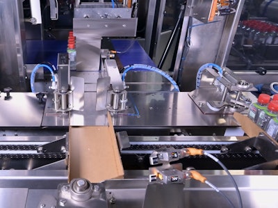 Seen here is one filled tray exiting the tray packer, a freshly erected tray ready to receive the next group of bottles, and the collated bottles staged and ready to enter the tray.