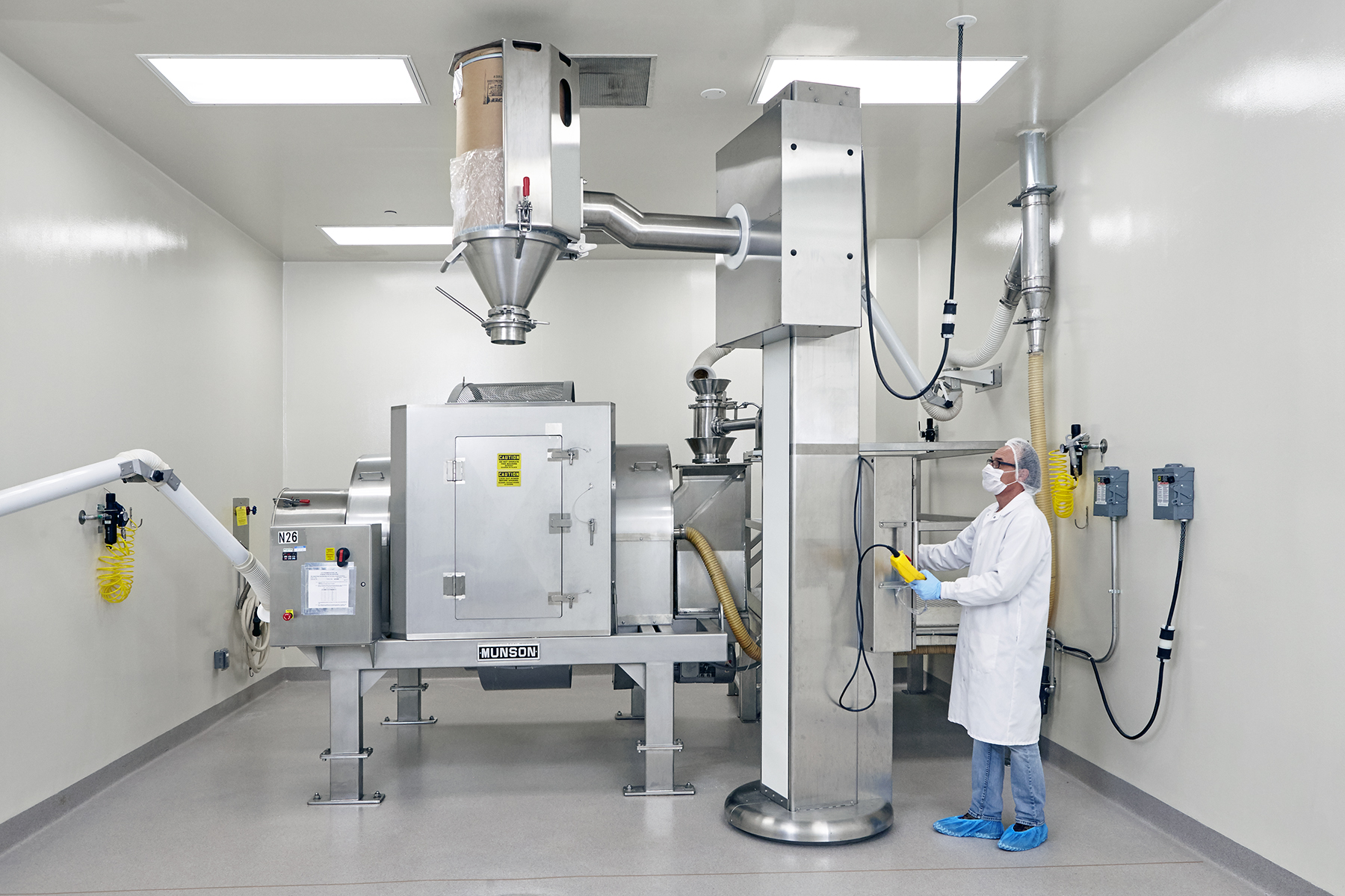 Drums containing each ingredient are lifted, aligned with the mixer's stationary inlet, and emptied&mdash;in a prescribed order according to the Master Batch Record.