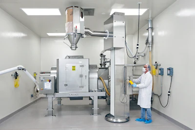 Drums containing each ingredient are lifted, aligned with the mixer's stationary inlet, and emptied&mdash;in a prescribed order according to the Master Batch Record.