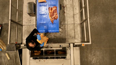 A worker loads pork bellies into the slicer.