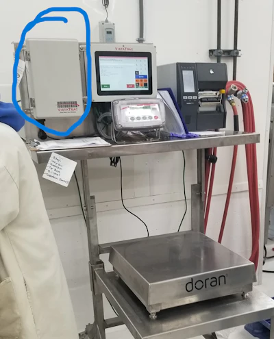 A TracBox system with enclosed scanner (circled) is used for weighing and labeling product.