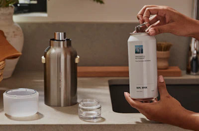 The aluminum refill can is opened and inserted into the reusable stainless steel vessel, where it locks into place for dispensing.