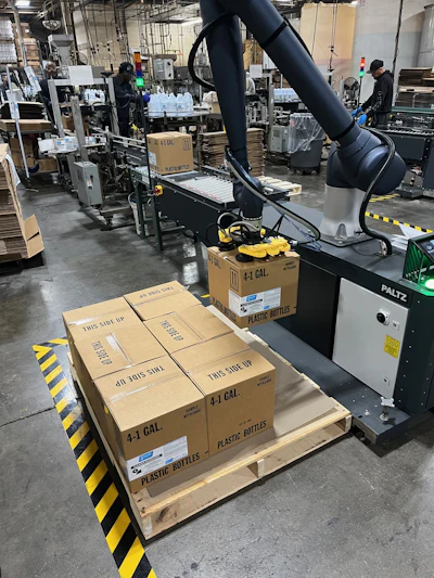 This cobot palletizing system handles cases containing four 1-gal containers with precision, using vacuum end-of-arm tooling to ensure consistent placement and stable pallet builds across varying configurations.